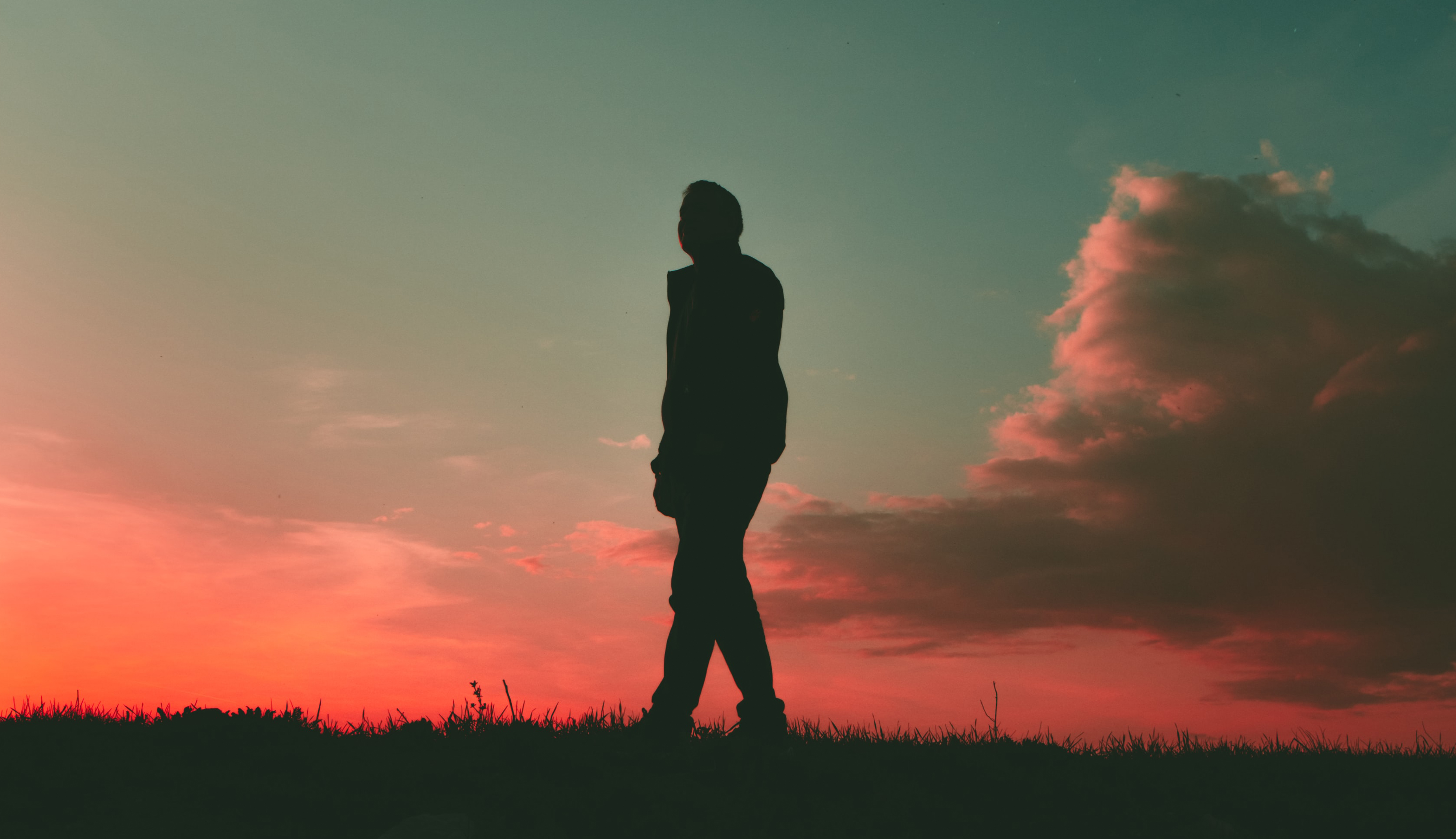 man wandelt over gras en kijkt naar zonsondergang