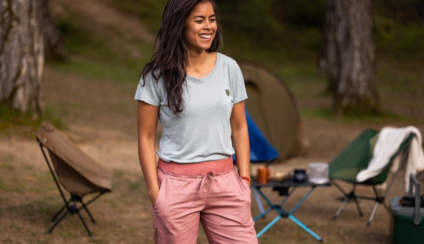 vrouw staat met handen in broekzakken voor haar kampeeropzet