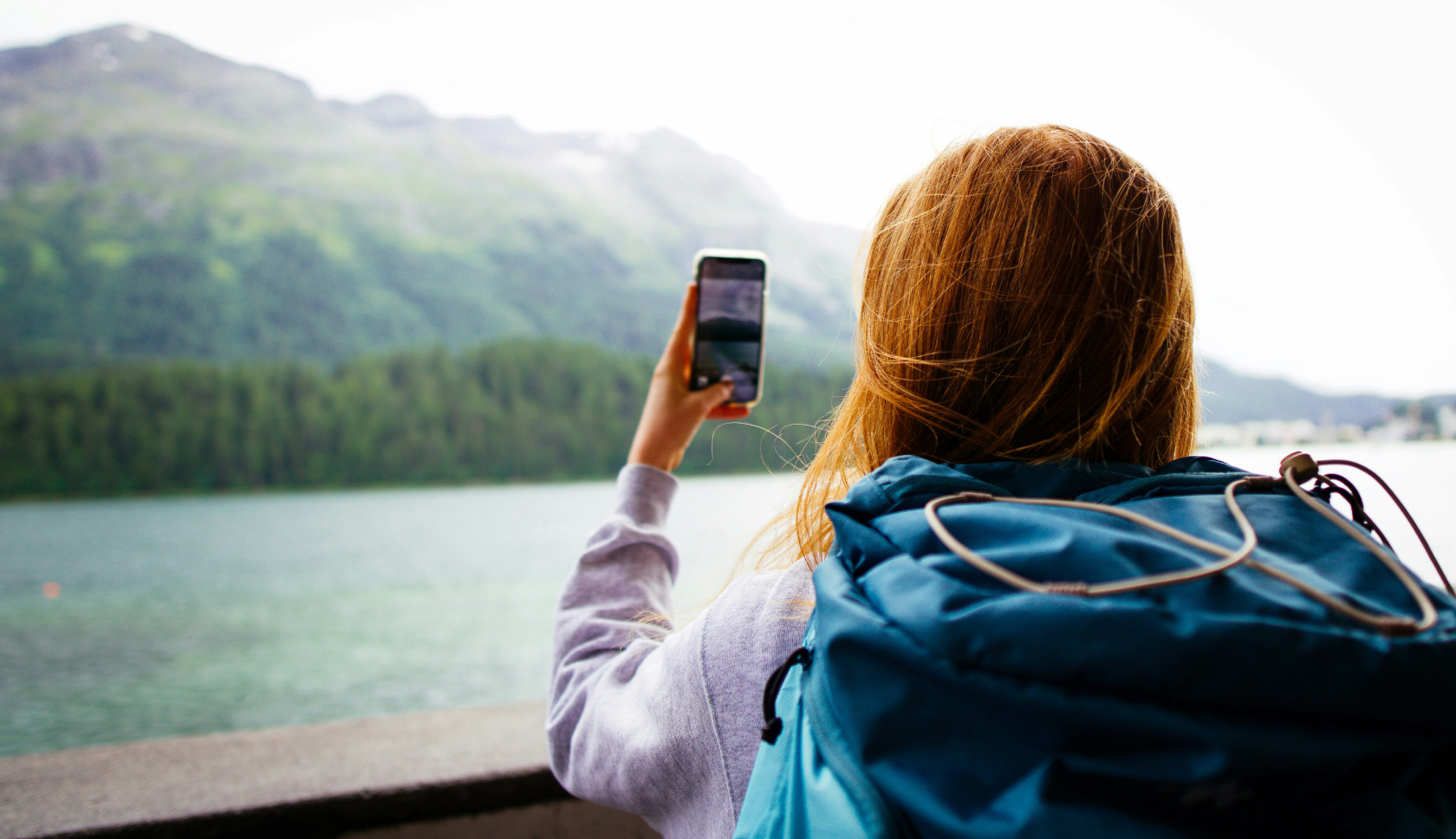 Een persoon maakt met haar telefoon een foto van fjorden