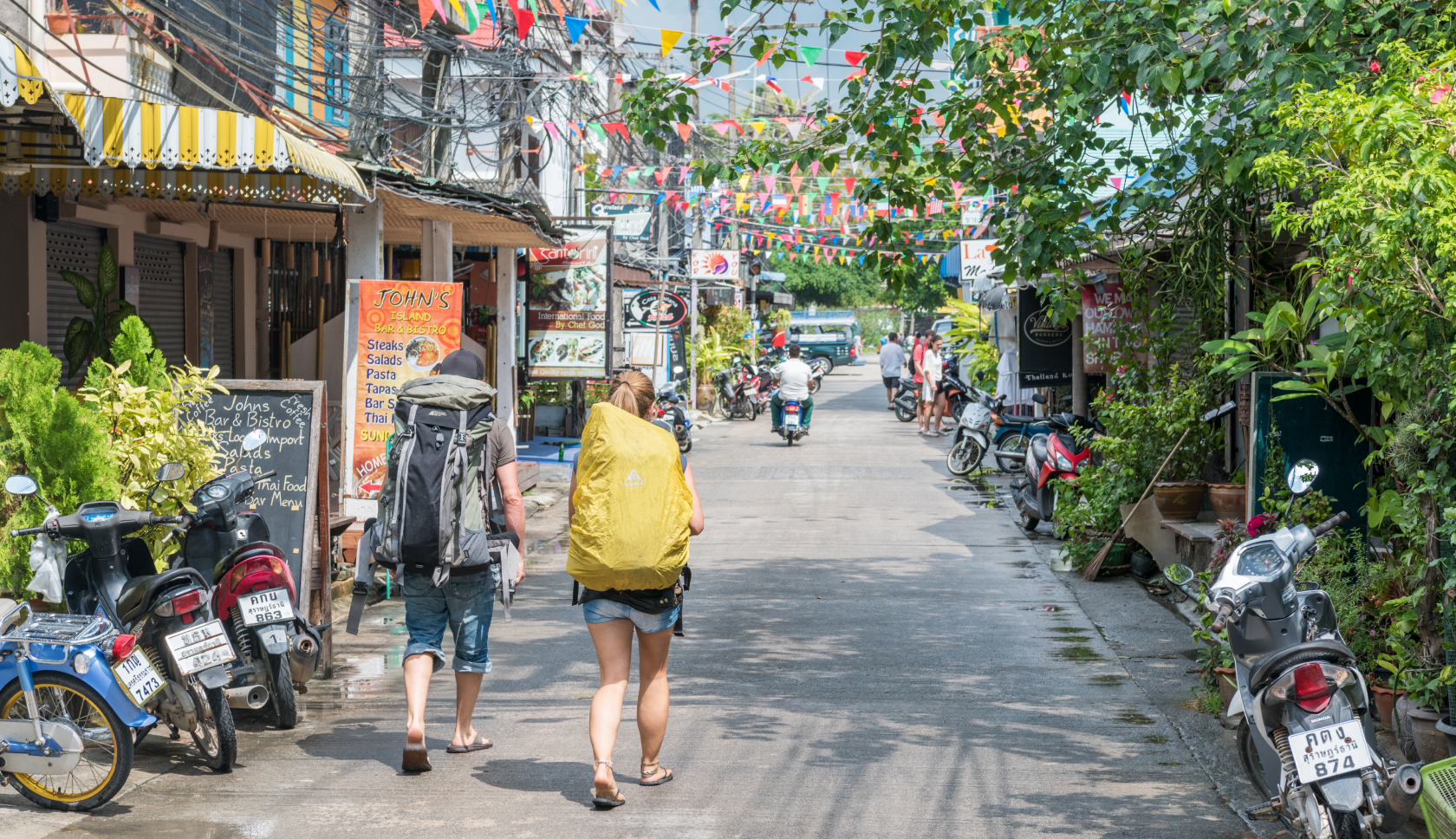 man en vrouw met backpacks wandelen door zonovergoten straat