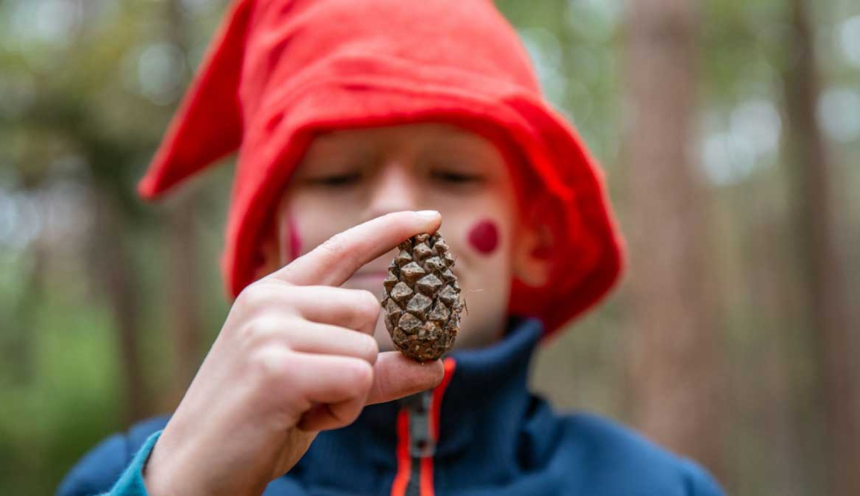 Een kind met een kaboutermuts doet een speurtocht in het bos