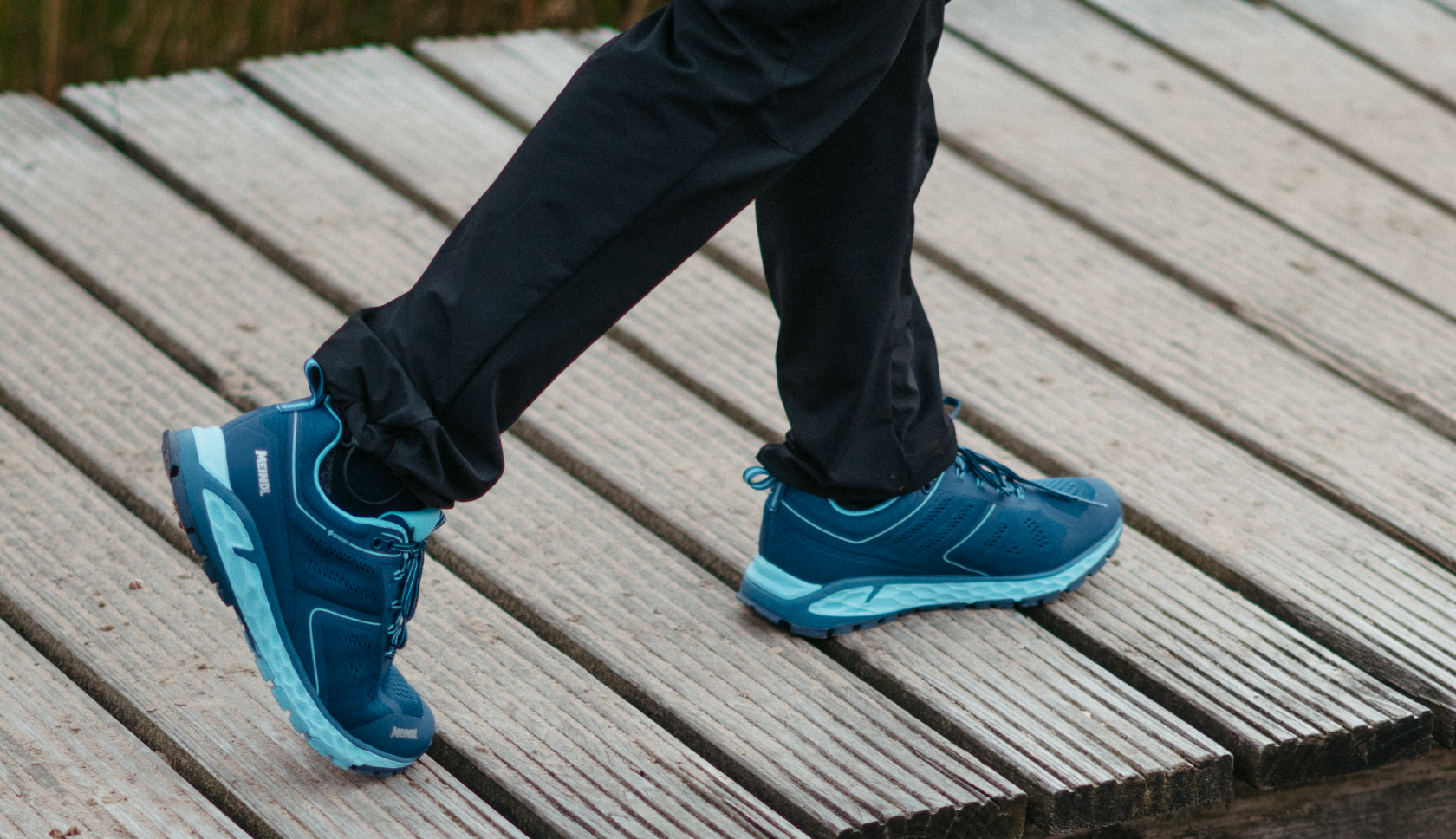 blauwe meindl comfort fit wandelschoenen lopen over een houten steiger