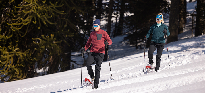 man en vrouw wandelen door de sneeuw met sneeuwschoenen