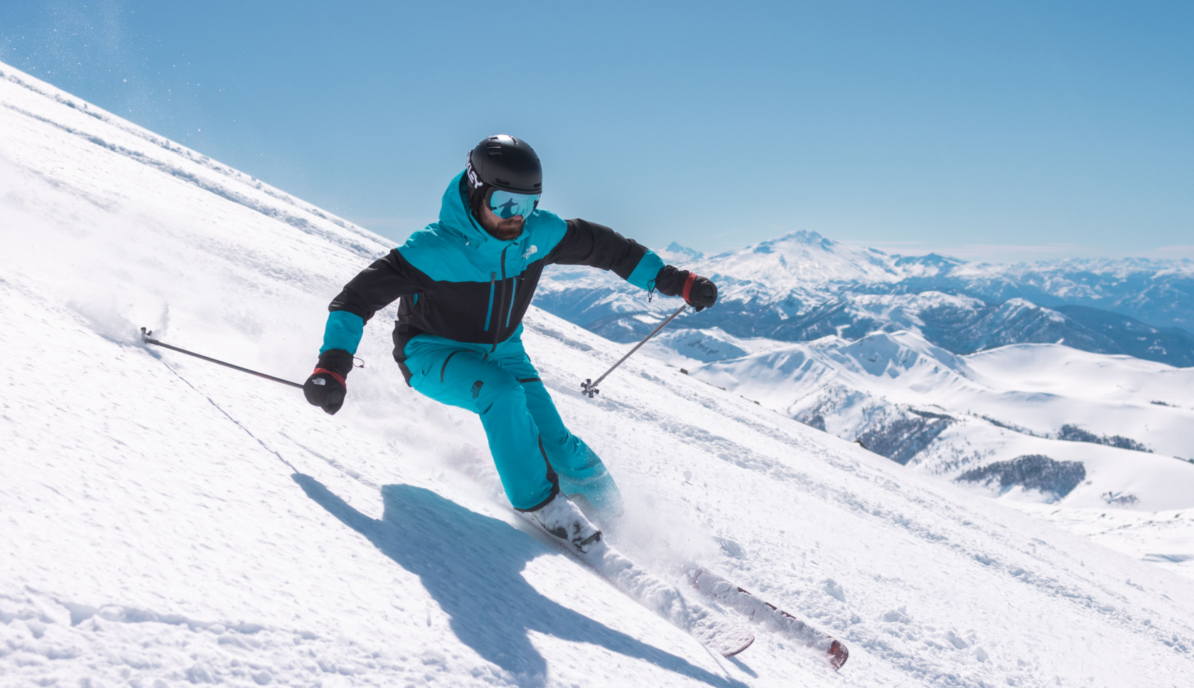 een skier in een felblauw skipak racet van een witte berg