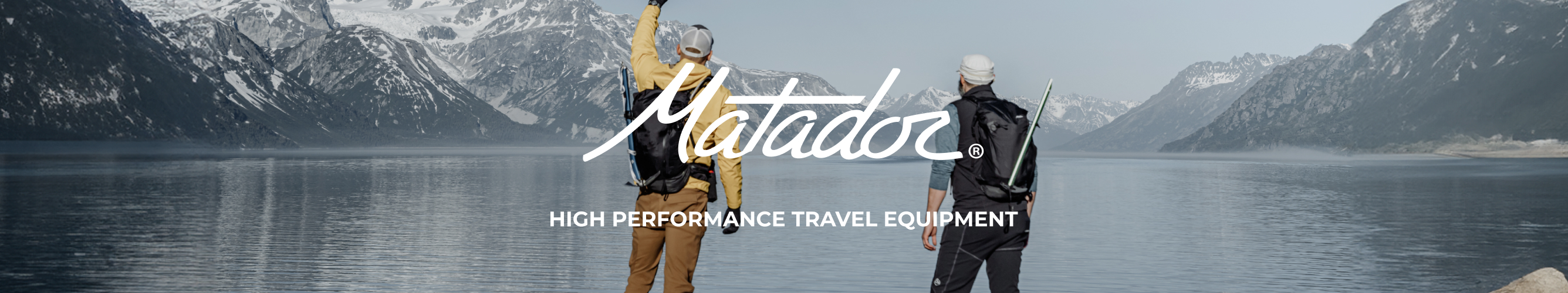 Twee wandelaars  met rugzakken kijken uit over een meer