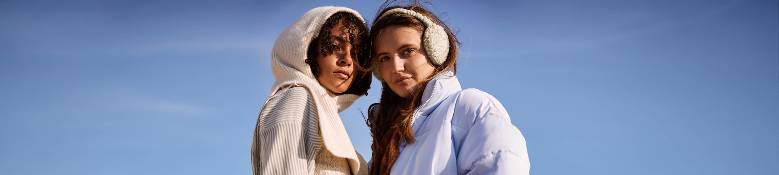 twee vrouwen met winterkleding aan tegen een strakblauwe lucht