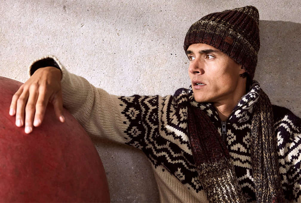 man in bruine trui met sjaal en muts op