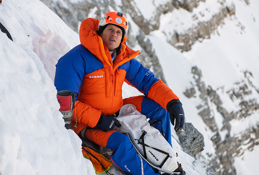 man in klimuitrusting rust op een besneeuwde berg