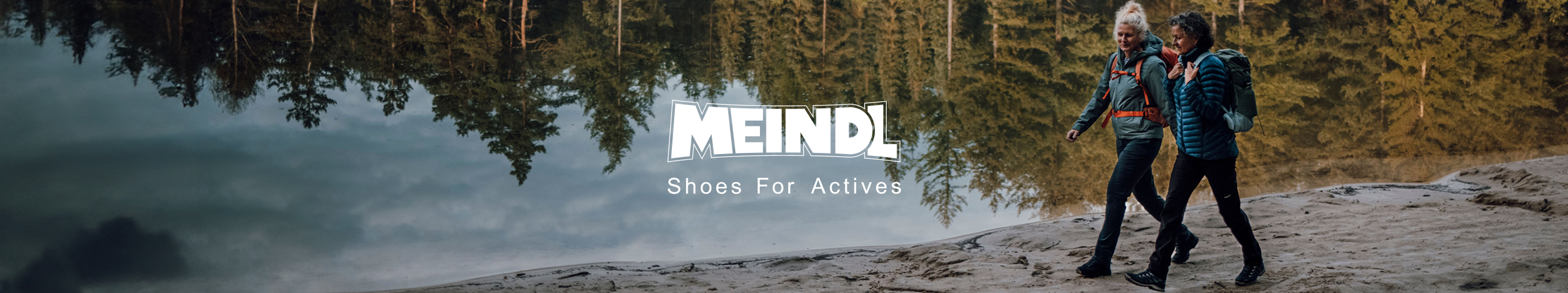 twee vrouwen wandelen langs een meer in het bos