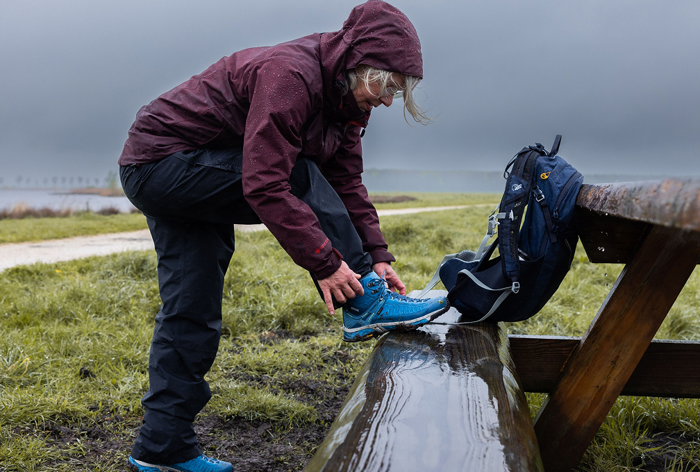 vrouw strikt veters op een natte picknick bank in een park