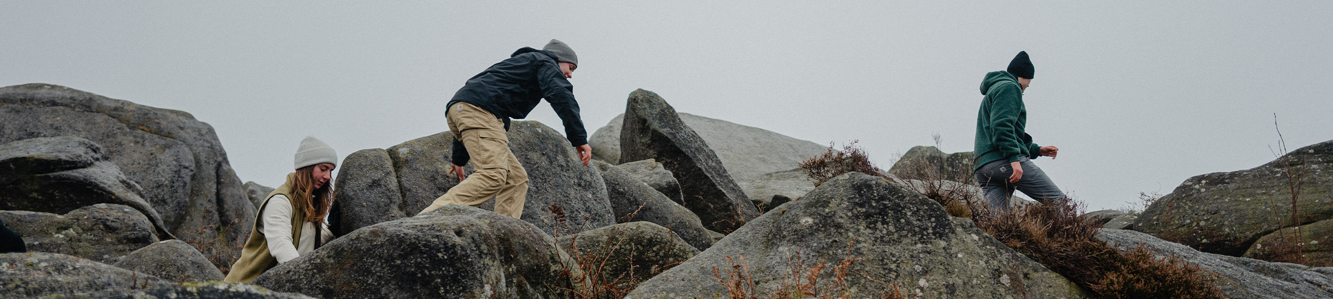 Drie wandelaars in Carhartt kleding tussen grote rotsen in de natuur