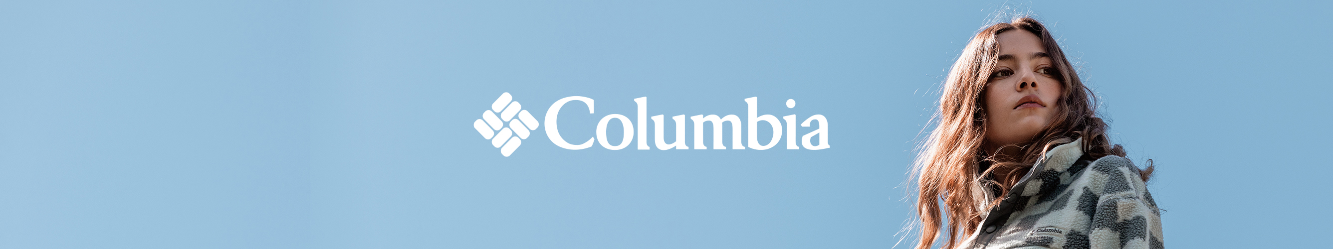 Model in Columbia-outdoorkleding tegen een blauwe achtergrond, met het Columbia-logo centraal in beeld.